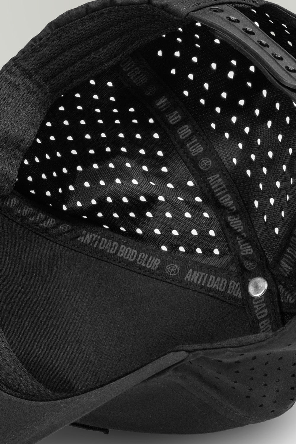 Close-up of a black hat with ventilation holes and brand logo.