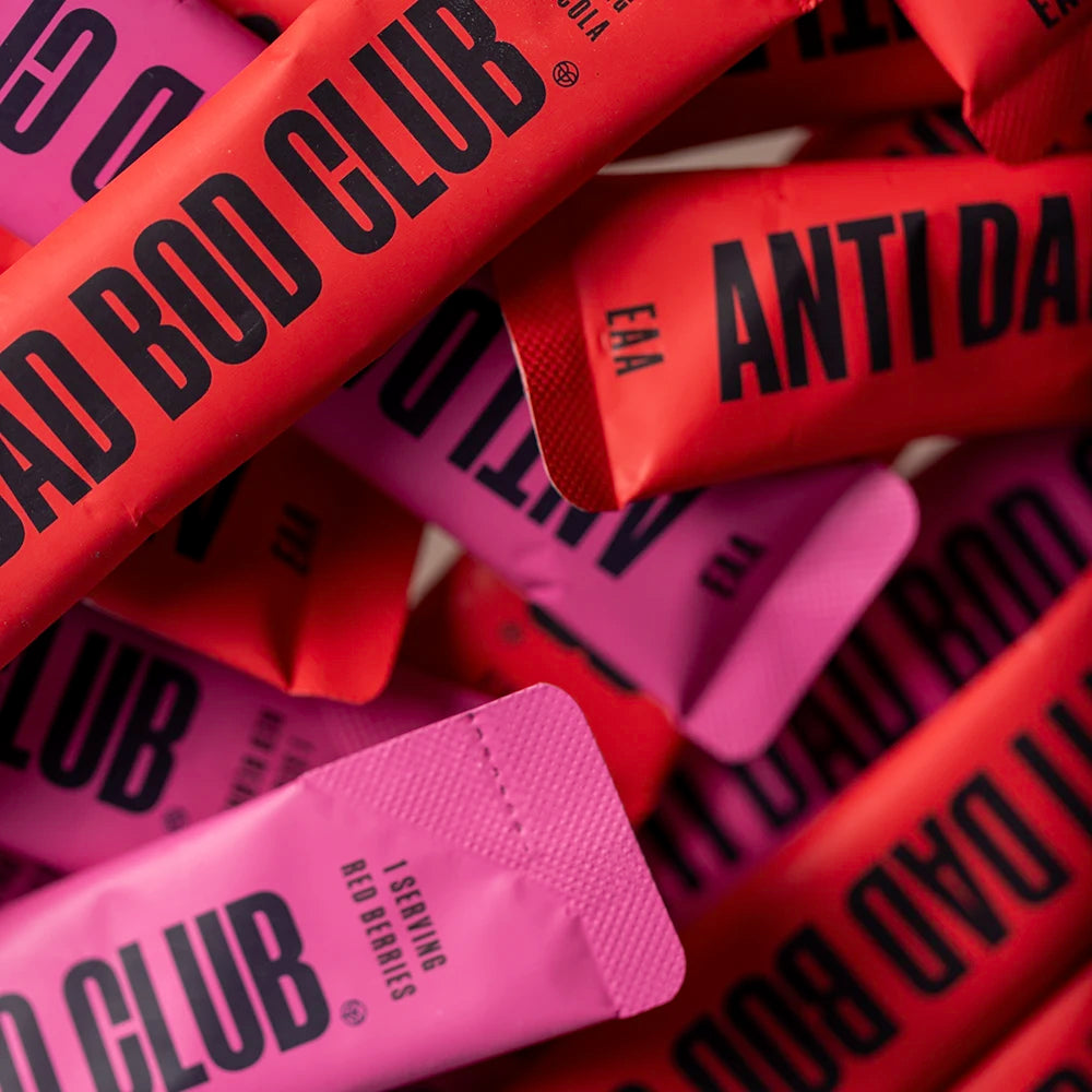 Close-up of 'Anti Bad Bod Club' Amino Acid sachets in pink and red packaging.