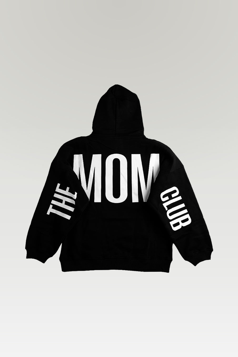 A black pullover hoodie shown from the back, featuring the words 'THE MOM CLUB' printed in bold white capital letters across the back and down both sleeves, set against a light gray gradient background.
